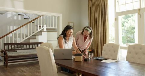 Senior Woman Sharing Joy with Gift from Friend in Cozy Home