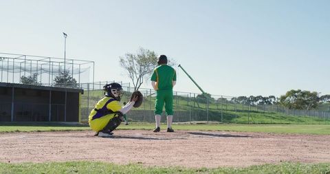 Baseball Batter Waiting at Plate with Catcher Crouching in Colorful Team Uniforms