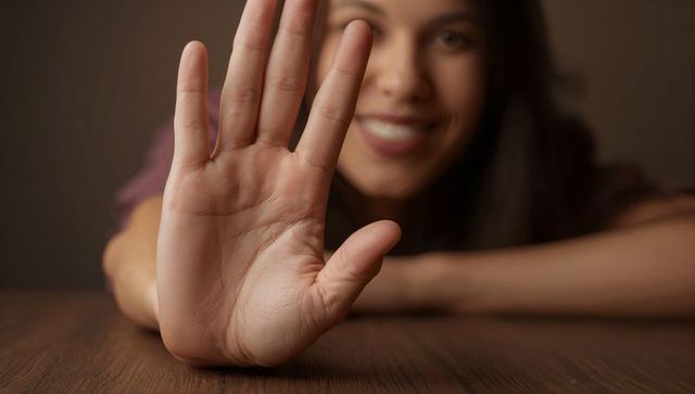 Woman extending hand for stop gesture at wooden table