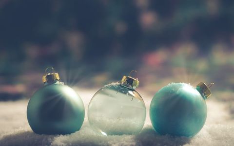 Blue glass christmas ornaments resting on snowy surface