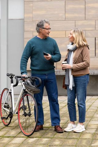 Middle-aged couple standing and chatting with bicycle coffee and smartphone