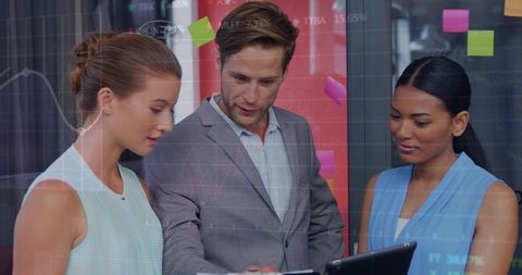 Team Collaborating Over Tablet Reviewing Data Analytics and Sticky Notes in Modern Office