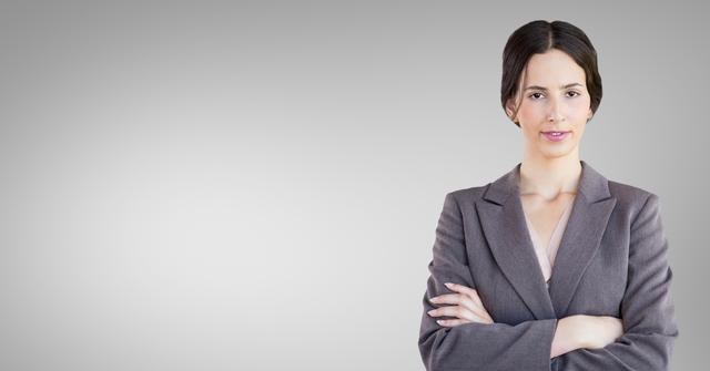 Confident businesswoman standing with arms crossed against grey background. Suitable for corporate and business industry themes, leadership materials, professional development resources, and career-focused content. Ideal for use in presentations, websites, flyers, and advertisements promoting business services and corporate environments.