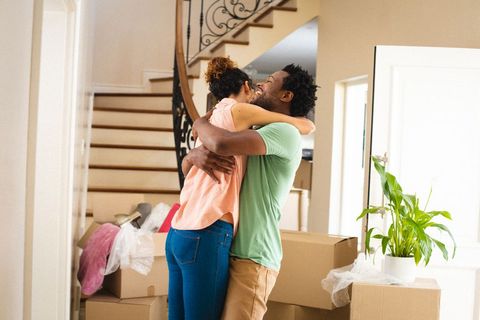Happy couple embracing in new home amid moving boxes