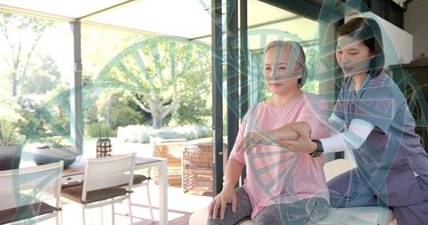 Caregiver supporting senior woman during seated physical therapy in bright living room