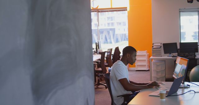 Side view of young black male executive working on computer at desk in modern office. Young black male executive sitting on desk 4k