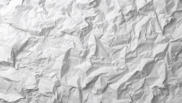 Crumpled white paper sheet filling frame revealing deep folds and soft shadows