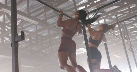 Two Women Performing Pull-Ups in Gym Emphasizing Fitness