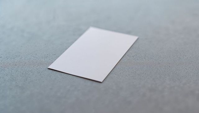 Blank white card on textured grey surface for minimalistic design