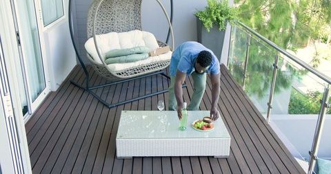 Man Arranging Refreshments on Modern Balcony Deck