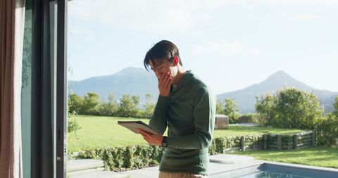 Man Holding Tablet Standing Outside Near Pool Experiencing Outdoor Serenity