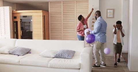 African American family decorating living room wall with purple balloons and stickers