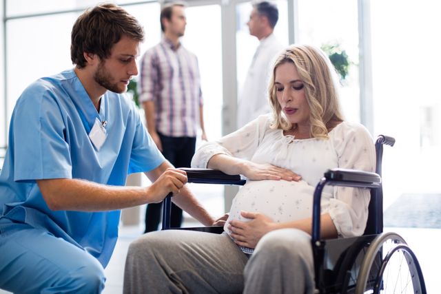 Male Doctor Assisting Pregnant Woman in Wheelchair at Hospital - Download Free Stock Photos Pikwizard.com