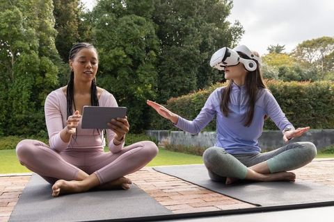 Outdoor vr-assisted yoga session with african american instructor guiding asian woman