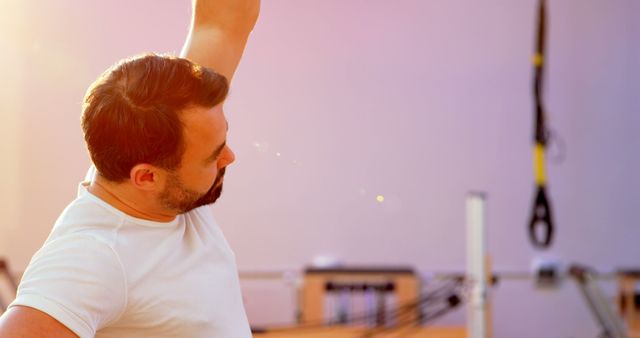 Man performing stretching exercise at an outdoor gym during sunset. This can be used for promoting fitness routines, healthy lifestyle advice, and outdoor exercise benefits.