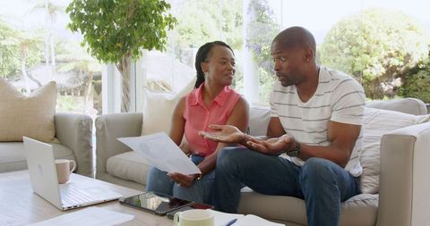 Couple consulting documents in living room setting