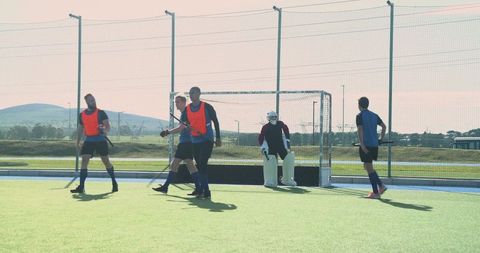Field Hockey Players Gather on Turf Near Goal