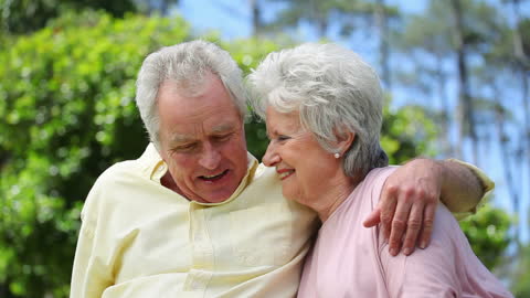 Senior Couple Embracing in Sunlit Park on Clear Day