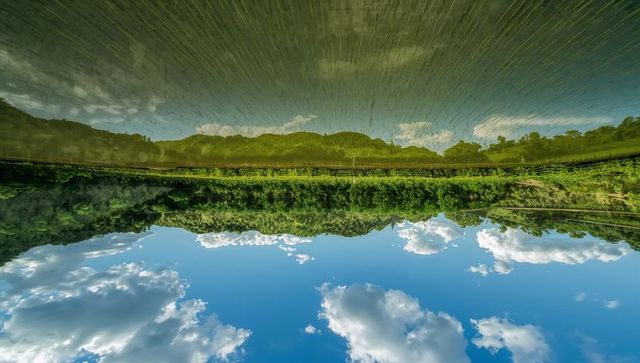Serene Water Reflections of Hills and Dramatic Clouds in Rural Setting