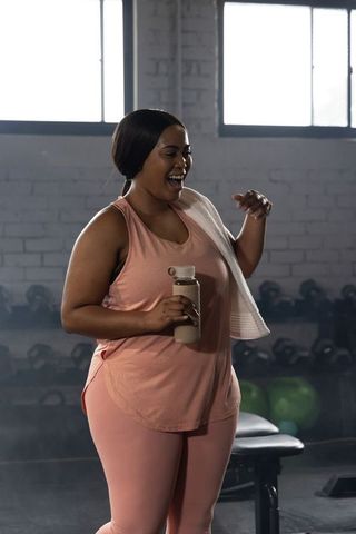 Confident african american woman smiling and cooling down after workout in pink activewear