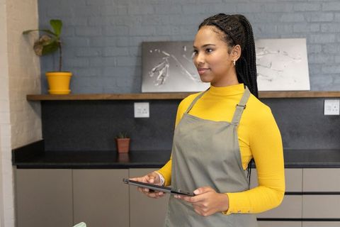 African american barista holding tablet in modern minimalist cafe interior mustard top