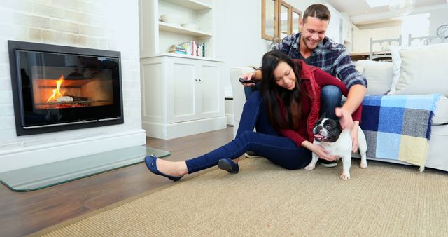 Happy couple playing with their dog in a cozy living room by the fireplace. This image can be used for home and lifestyle publications, pet care advertisements, or content about family and togetherness.