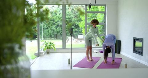 African american yoga instructor teaching home yoga session with student on purple mats