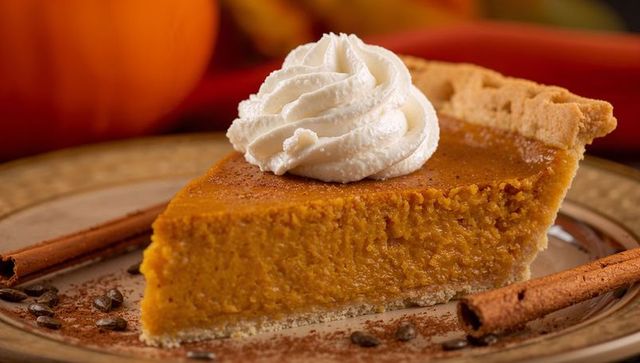 Creamy Pumpkin Pie Slice with Whipped Cream and Cinnamon Sticks on Ceramic Plate