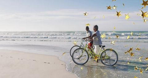 Senior couple walking cruiser bikes along sunny beach with gold star overlay