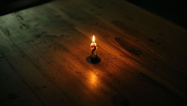 Glowing question mark candle on rustic wooden surface