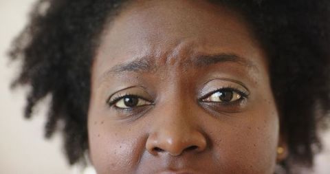 African american woman worried closeup with eyeliner, eyeshadow and gold stud earring