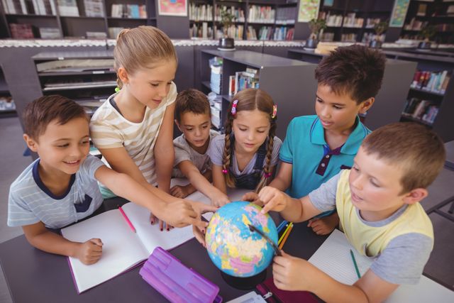 Group of schoolchildren gathered around a globe in a library, engaging in a geography lesson. Ideal for educational content, school brochures, learning resources, and articles on childhood education and teamwork.