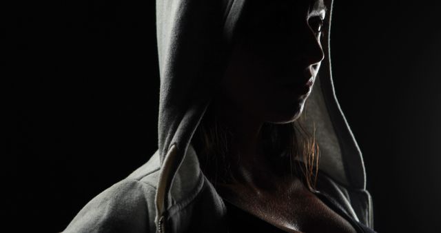 Portrait of focused caucasian strong woman in grey hoodie with copy space on black background. Strength and fitness concept.