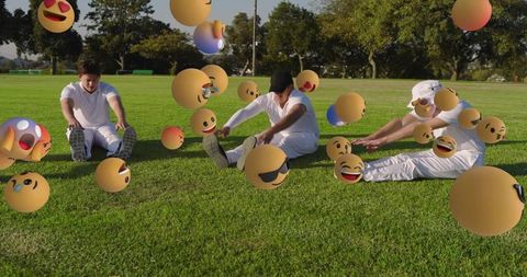 Men stretching on park lawn with floating emoji spheres creating playful team fitness concept