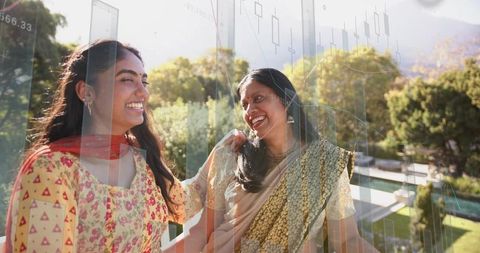 South asian mother and daughter laughing on balcony wearing kurta and saree with data overlay