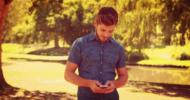 Young Man Texting on Smartphone in Sunny Park - Download Free Stock Images Pikwizard.com