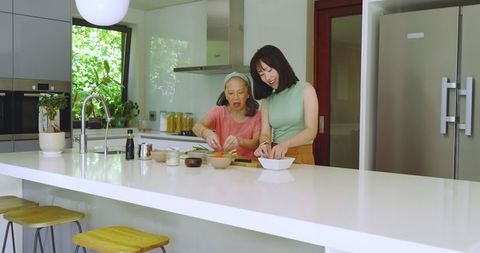 Mother and Daughter Having Fun Cooking Together in Modern Kitchen