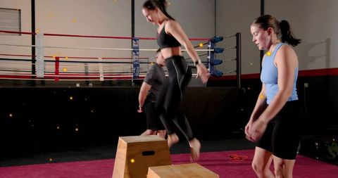 Woman performing box jump in boxing gym during plyometric agility and strength training