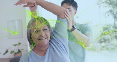 Caregiver helping senior woman stretch arm for home therapy and wellness support