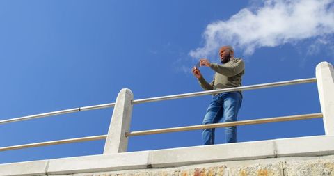 Man taking photos with smartphone against clear blue sky