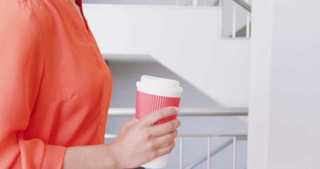 Woman holding reusable coffee cup in modern office building - Download Free Stock Images Pikwizard.com