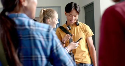Teenagers socializing in school hallway with backpacks