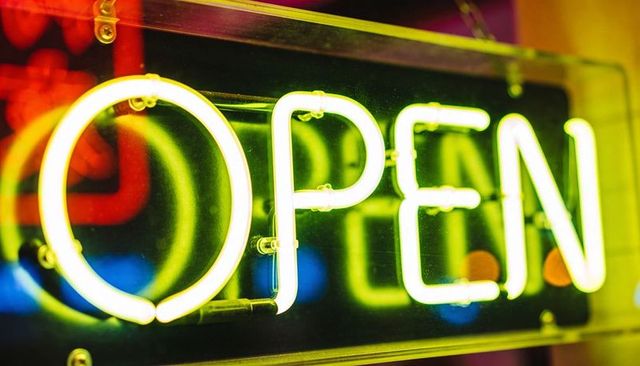 Glowing Neon OPEN Sign Casting Warm Light on Storefront Glass with Bright Reflections