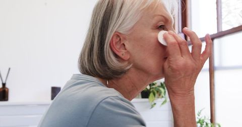 Senior woman practicing skincare routine in bright bathroom
