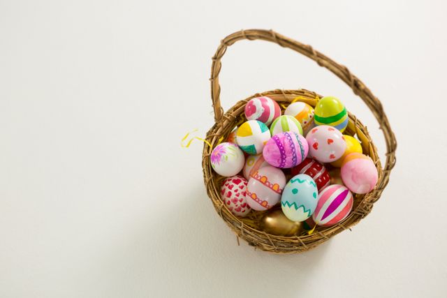 Basket filled with various colorful painted Easter eggs on white background. Ideal for Easter-themed promotions, holiday greeting cards, festive decorations, and spring celebration advertisements.