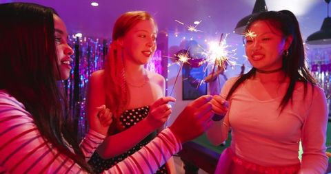 Young Diverse Friends Celebrating with Sparklers in Colorful Lounge Party Night Scene