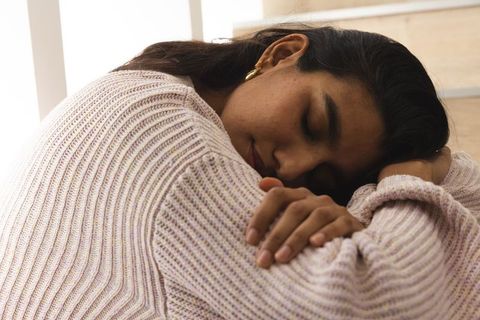 Woman Finding Solace Leaning on Wooden Steps by Sunlit Window