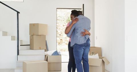 Couple Joyfully Embracing in New Home amidst Packing Boxes