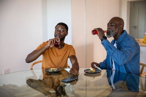 Father and son enjoying avocado toast and refreshing drinks in kitchen