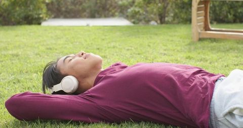Man Relaxing on Grass with Headphones Enjoying Nature